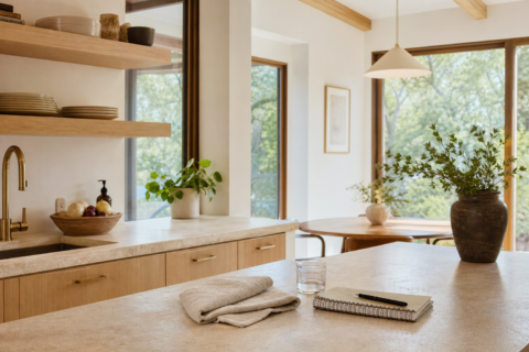Clear kitchen counter with linen towel, plant, notebook, and warm natural light.