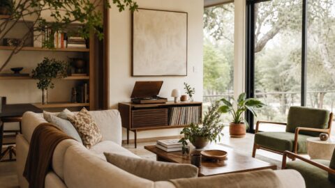 Modern organic living room with records, books, plants, conversation seating, and large windows with no visible TV.